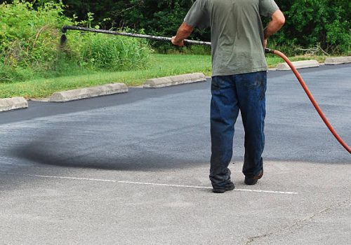 Spraying new sealer coat on an asphalt parking lot.